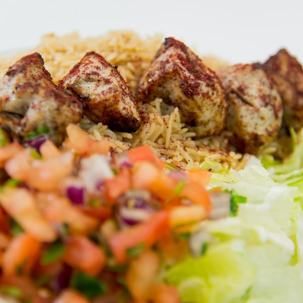 Close-up of Ruz Bukhari's chicken kebab with rice, fresh tomato salsa, and lettuce.