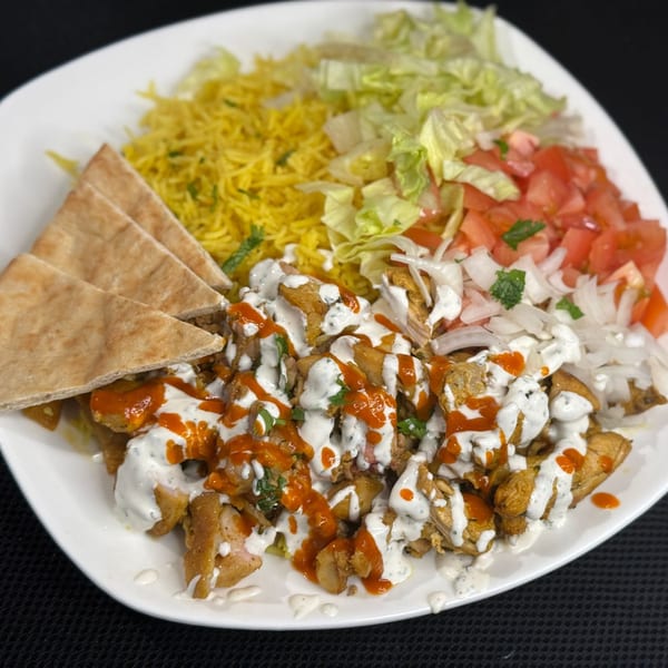 Ruz Bukhari's chicken shawarma plate with rice, salad, pita bread, and white and red sauces.
