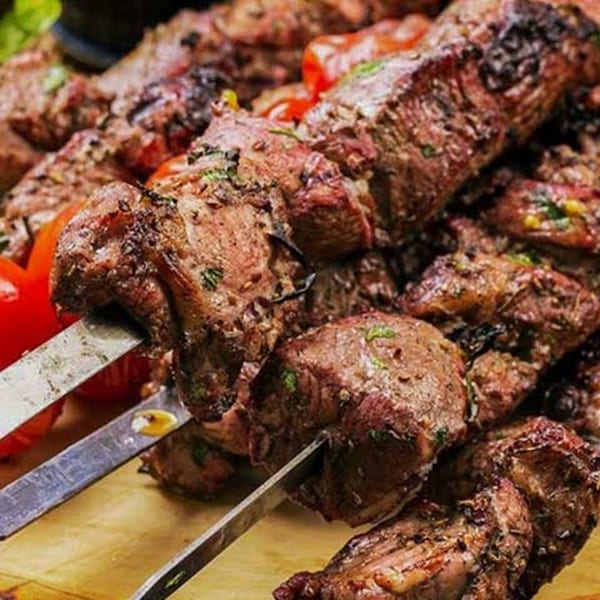 Close-up of Ruz Bukhari's grilled meat skewers with tomatoes, showcasing Afghan Halal cuisine.