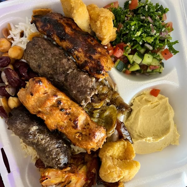 Ruz Bukhari's Afghan platter with grilled meats, rice, beans, salad, hummus, and fried items.