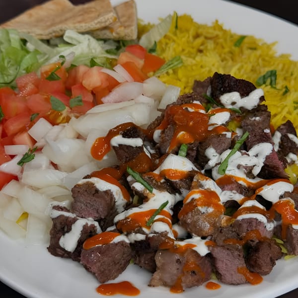 Ruz Bukhari's Afghan beef dish with yellow rice, salad, and pita bread.